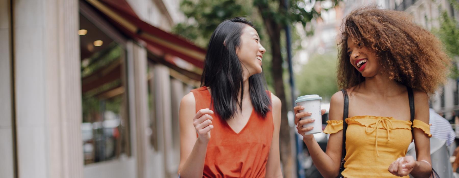 a couple of women walking down a sidewalk and laughing