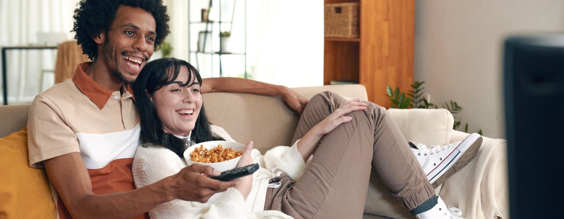 a man and a woman sitting on a couch eating pizza